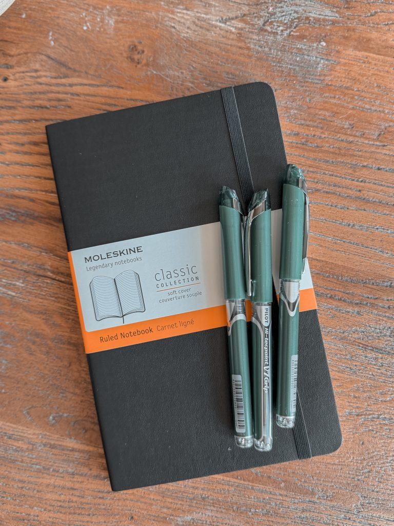 Black Moleskine notebook with green Pilot rollerball pens for back to school